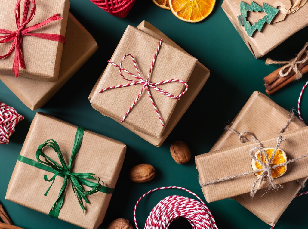 Weihnachtsgeschenke in Packpapier auf dunkelgrünem Hintergrund mit Orangenscheiben und Zimtstangen