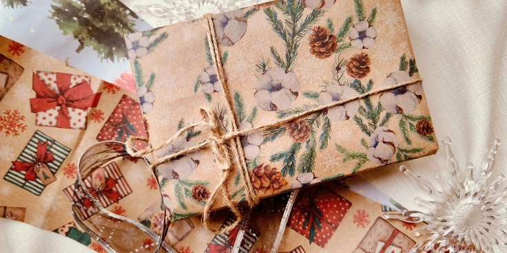 Weihnachtspäckchen in naturpapier mit kiefern-motiv und juteschnur