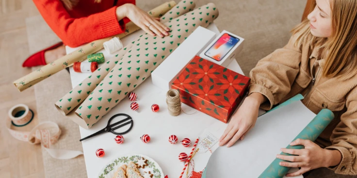 Zwei personen bereiten geschenkpapier und deko fürs einpacken vor