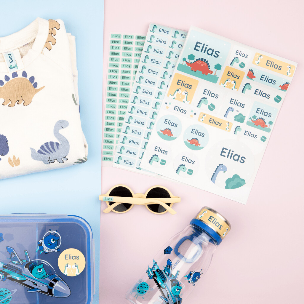 Ein set mit großen namensaufklebern mit dem text "elias" und einem dinosaurier-design, zusammen mit passenden personalisierten accessoires und weiteren aufkleber-sets in verschiedenen größen