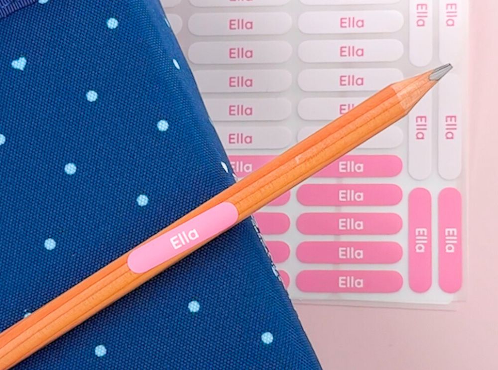 Namensaufkleber und bügeletiketten – personalisierte lösungen für jeden bedarf 2 Rosa stifte-aufkleber mit text "ella", der auf einen bleistift aufgeklebt ist.