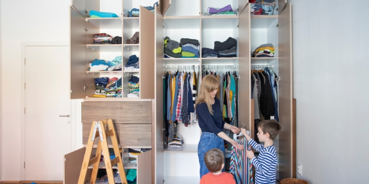 Kleberli's winterhelfer: praktische hilfsmittel für einen organisierten familienalltag 1 Mutter und kinder organisieren gemeinsam einen kleiderschrank, winterkleidung wird sortiert.