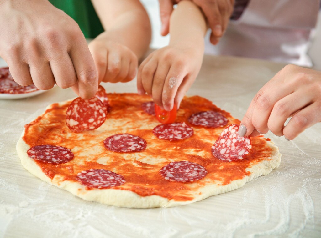 Kinder- und erwachsenenhände belegen gemeinsam eine pizza