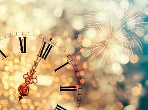 Vintage clock close to midnight with fireworks in the background.