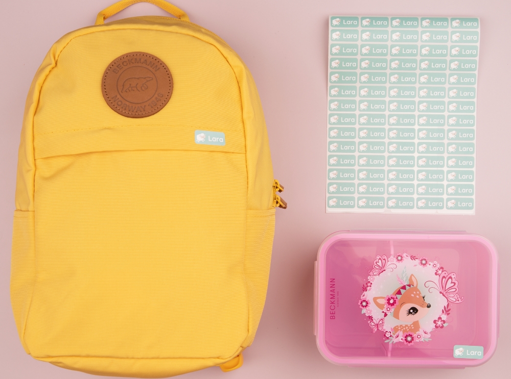 Kindergarten-erstausstattung komplett: was dein kind wirklich braucht 1 Gelber rucksack, rosa brotdose und ein set mit grünen, personalisierten namensaufklebern