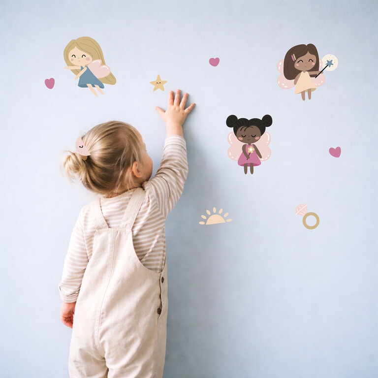 Mädchen klebt Feen Wandsticker an die Wand